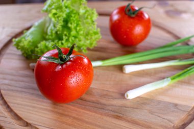 Ahşap zemin üzerinde salata ve soğan ile sulu kırmızı domatesler. Vejetaryen yemeği. Olgun domatesler, bir damla suyla..