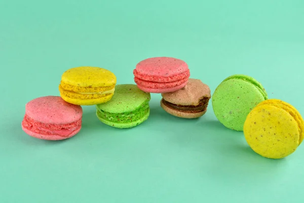 Macaroons on a turquoise background. Multi-colored macaroons on a colored background. Apetite multicolored cookies for dessert, on a turquoise background.