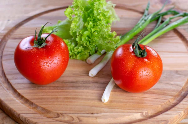 Ahşap zemin üzerinde salata ve soğan ile sulu kırmızı domatesler. Vejetaryen yemeği. Olgun domatesler, bir damla suyla..