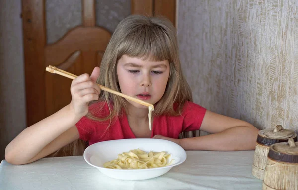 子供は牛乳を飲んでいる 女の子はクロワッサンを食べてミルクを飲む 選択的焦点 — ストック写真