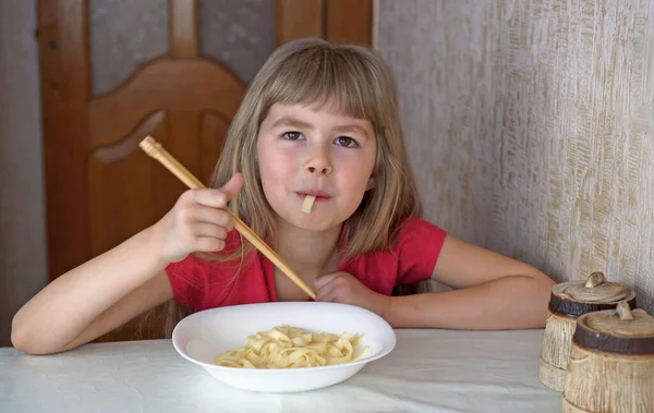 子供は牛乳を飲んでいる 女の子はクロワッサンを食べてミルクを飲む 選択的焦点 — ストック写真