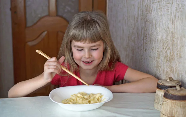 子供は牛乳を飲んでいる 女の子はクロワッサンを食べてミルクを飲む 選択的焦点 — ストック写真