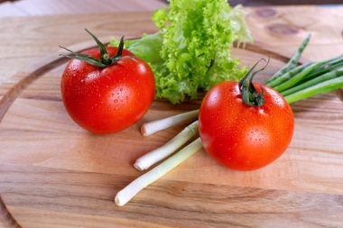 Ahşap zemin üzerinde salata ve soğan ile sulu kırmızı domatesler. Vejetaryen yemeği. Olgun domatesler, bir damla suyla..