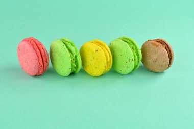 Turkuaz arka planda makarna. Renkli arka planda çok renkli badem kurabiyeleri. Tatlı olarak turkuaz arka planda çok renkli kurabiyeler..