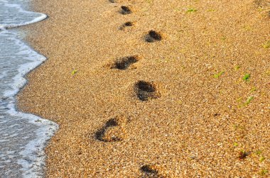 Kumdaki deniz. Ayak sahilde çıplak ayak izleri