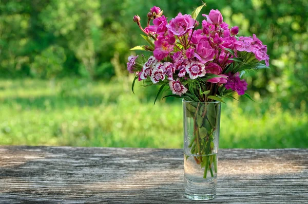 Bouquet of small carnations on a table in the garden — Stock Photo, Image