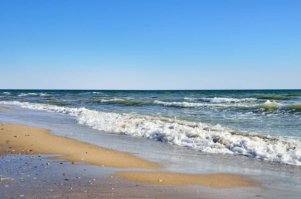 Τα κύματα της θάλασσας ξεπλένουν την παραλία από τον γαλάζιο ουρανό. Τοπίο σε μια άγρια παραλία. — Φωτογραφία Αρχείου