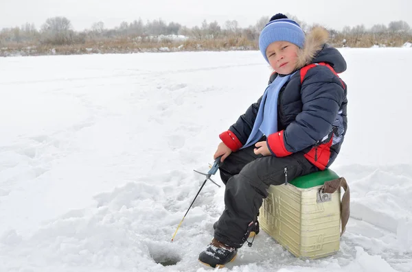 Little boy fishing on the frozen river in winter — Stock Photo, Image