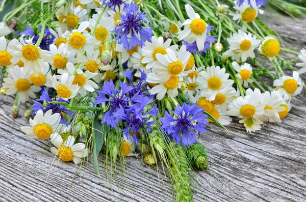 A bouquet of daisies and cornflowers on wooden table. Postcard of wild flowers — Stock Photo, Image