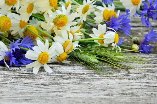 A bouquet of daisies and cornflowers on wooden table. Postcard of wild flowers
