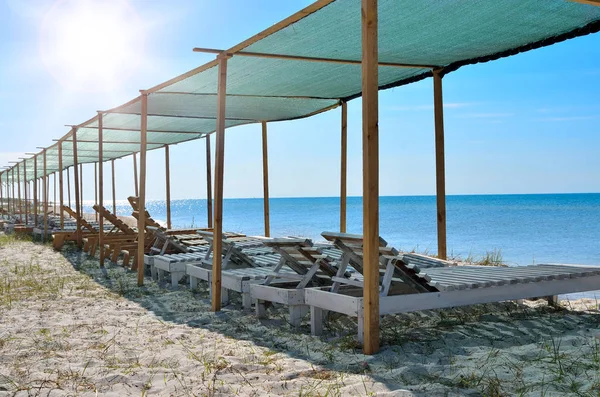 Lettini in legno sullo sfondo del mare blu. Villaggi turistici, vacanze e paesaggi marini — Foto Stock