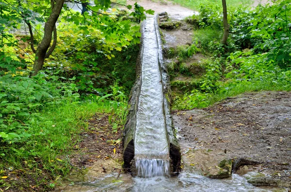 Fluxo de água flui na sarjeta de madeira no parque — Fotografia de Stock