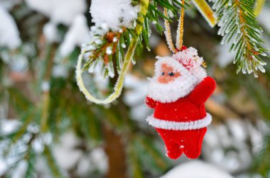 Kar, oyuncaklarla süslenmiş Noel ağacının dallarını kapladı. Noel Baba şeklinde yeni yıl süslemeleri..