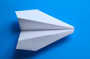 Mavi arka planda beyaz kağıttan yapılmış uçak..