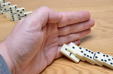 Domino etkisi, zincirleme reaksiyon bir insan eli tarafından durdurulur..
