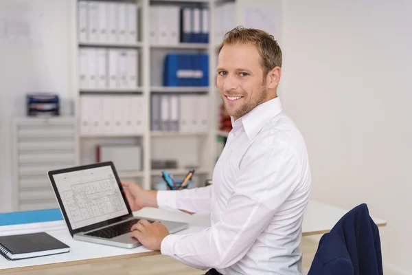 Gelukkig jonge zakenman die werken op een werkblad — Stockfoto