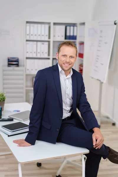 Smart relaxed businessman sitting on a table — Stockfoto
