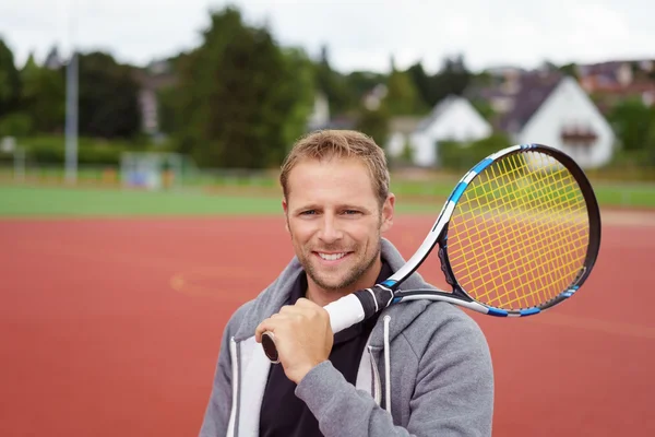 Mutlu genç adam bir tenis raketi taşıyan — Stok fotoğraf