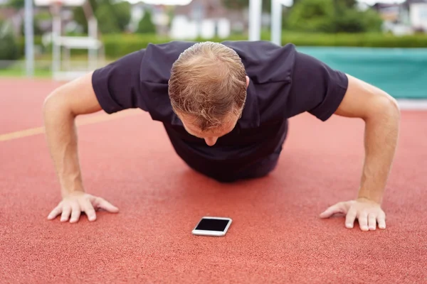 Man warming up doing press-ups on a race track — Stock Photo, Image
