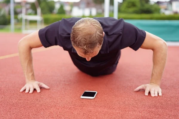 Man warming-up doen ligsteunen op een racecircuit — Stockfoto