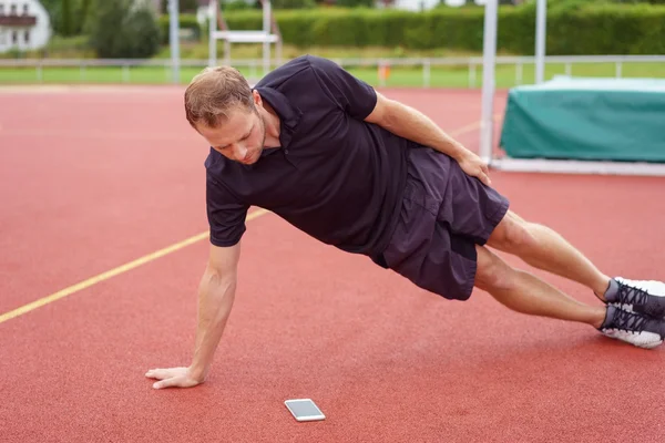 Man doing planks while looking at smart phone — Stock fotografie