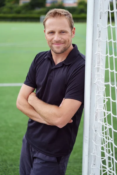 Sonriente hombre apoyado en los postes de gol — Foto de Stock