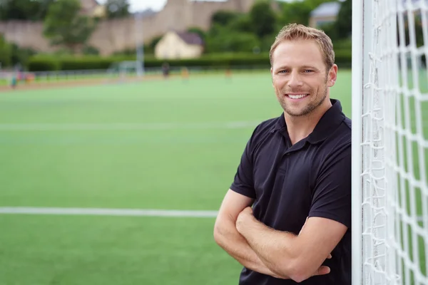 Ontspannen gelukkig voetbaltrainer leunend op het doel — Stockfoto