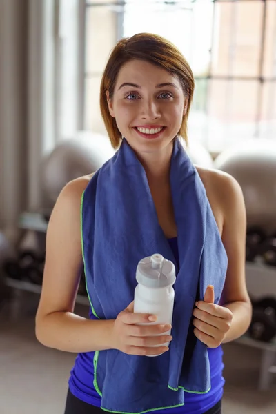 Woman with water bottle and towel around neck — Stock Photo, Image