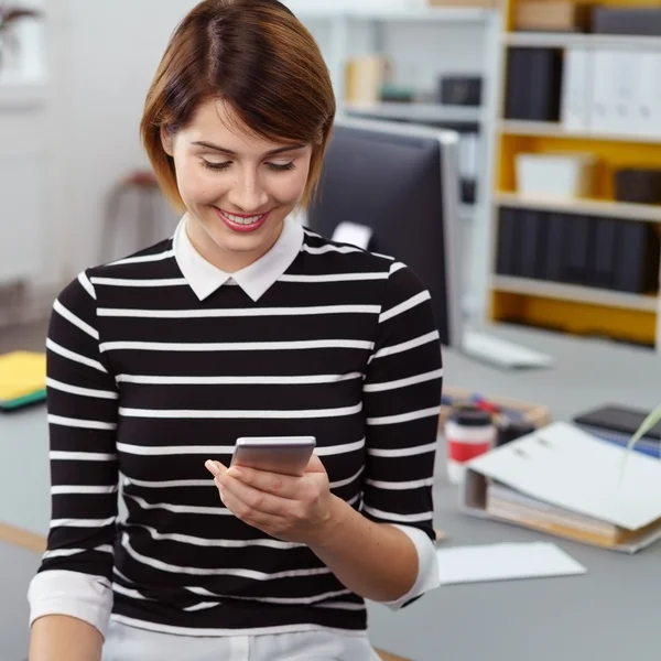 Wanita bahagia melihat telepon saat di tempat kerja — Stok Foto