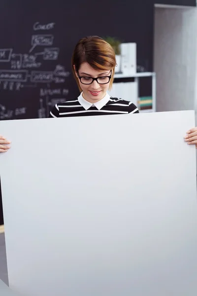 Mujer sosteniendo un gran cartel en blanco en la oficina — Foto de Stock