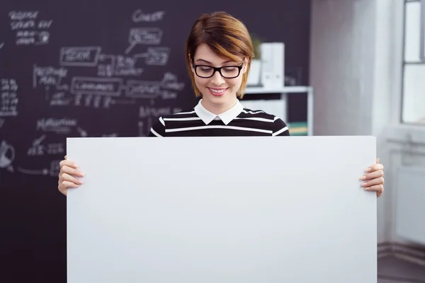 Frau blickt auf großes Blankoschild im Büro herab — Stockfoto