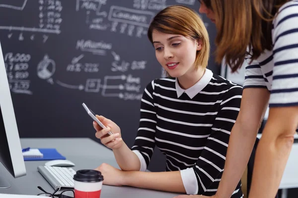 Arbeiterinnen schauen in der Schule aufs Handy — Stockfoto