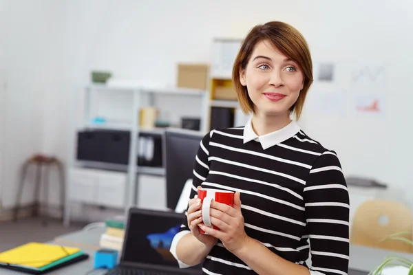 Amüsierte junge Frau beobachtet jemanden im Büro — Stockfoto