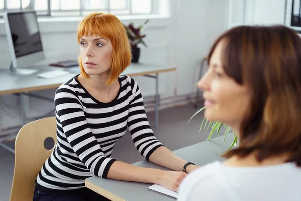 Two businesswomen listening to a colleague — Stockfoto
