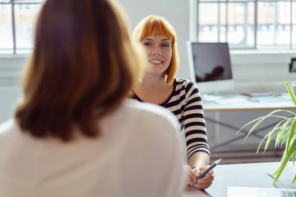 Smiling businesswoman chatting to a coworker — Stock fotografie