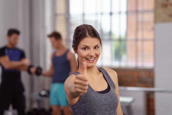 Zeker jonge vrouw met duimen omhoog op sportschool — Stockfoto