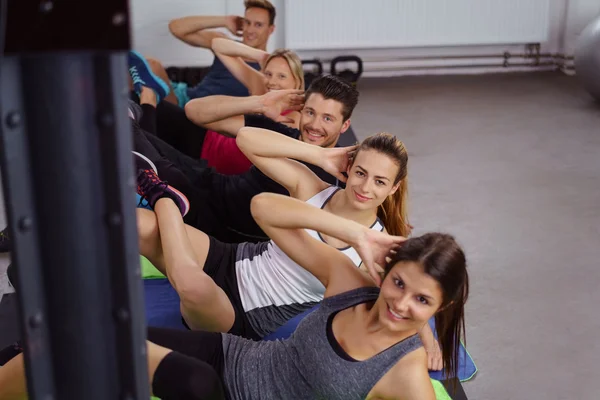 Hombres y mujeres alegres haciendo ejercicios abdominales —  Fotos de Stock