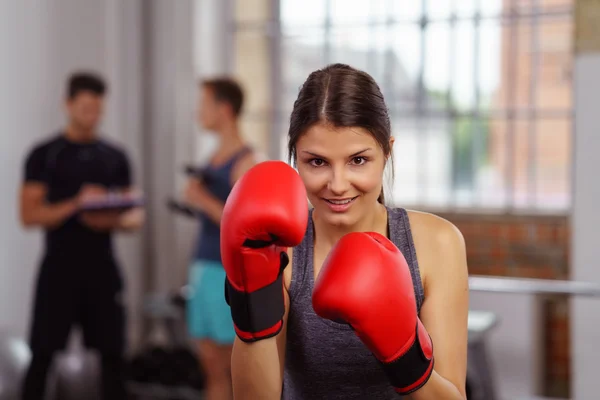 Giovane femmina sorridente in guanti da boxe rossi — Foto Stock