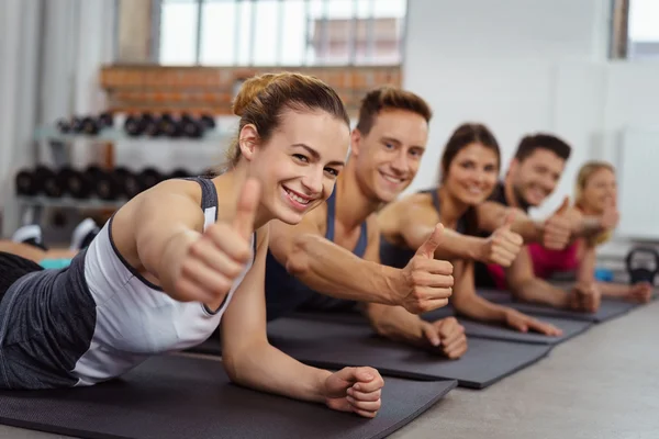 Group laying on mats while doing thumb up gesture — Stock Photo, Image