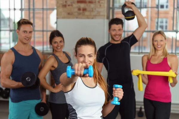 Excited woman showing off dumbbells and pointing — Stockfoto