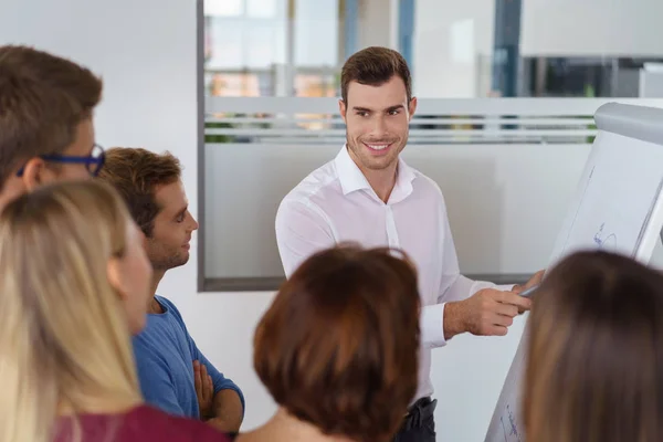 Smiling man showing coworkers something on board — Stock Photo, Image