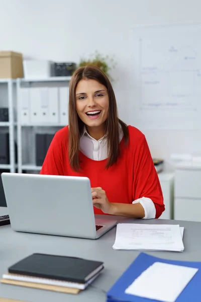 Jovem empresária feliz sentada em sua mesa — Fotografia de Stock