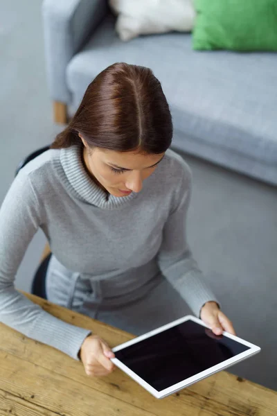 Serious young woman sitting reading her tablet — Stock Photo, Image