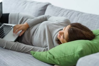 Relaxed young woman using a laptop computer clipart