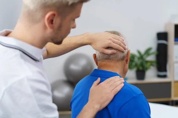 Fisioterapeuta masajeando cuello de paciente mayor —  Fotos de Stock