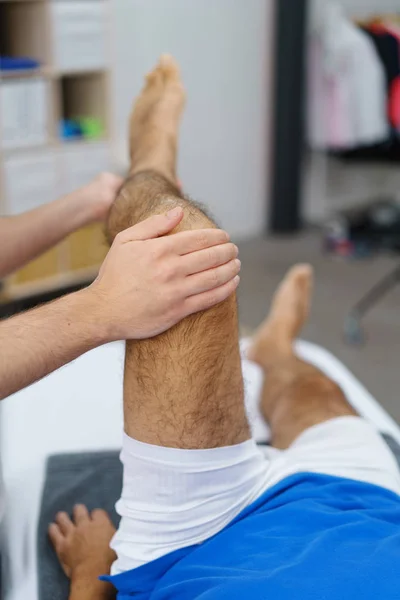 Fisioterapeuta manipula homem idoso perna — Fotografia de Stock