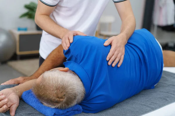 Fisioterapeuta fazendo massagem ao homem idoso — Fotografia de Stock