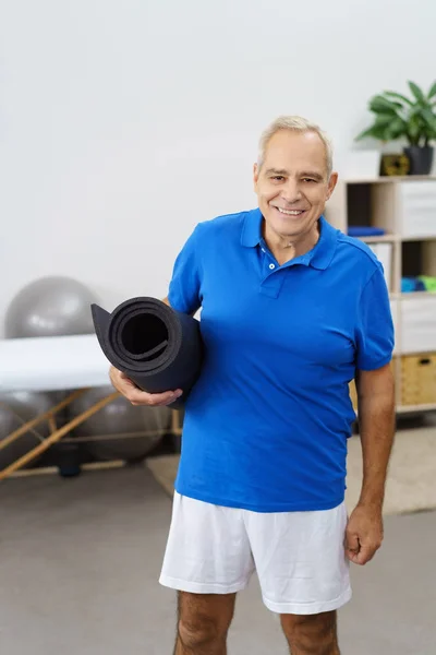 Elderly man holding gym mat — Stock Photo, Image