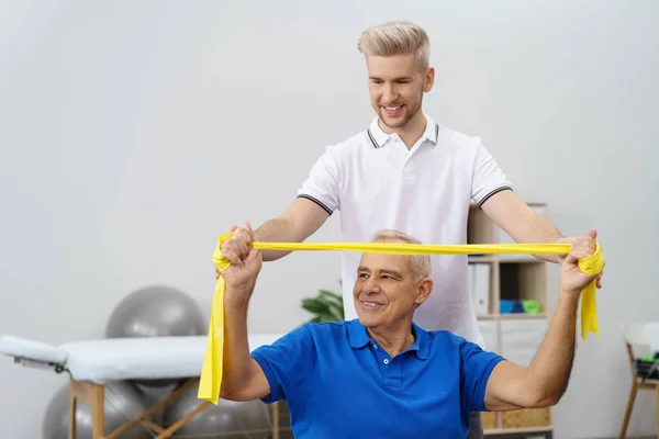 Entrenador haciendo ejercicio con un hombre jubilado — Foto de Stock