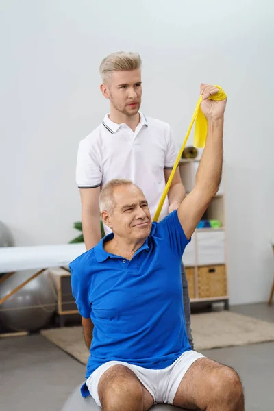 Entrenador haciendo ejercicio con un hombre jubilado — Foto de Stock